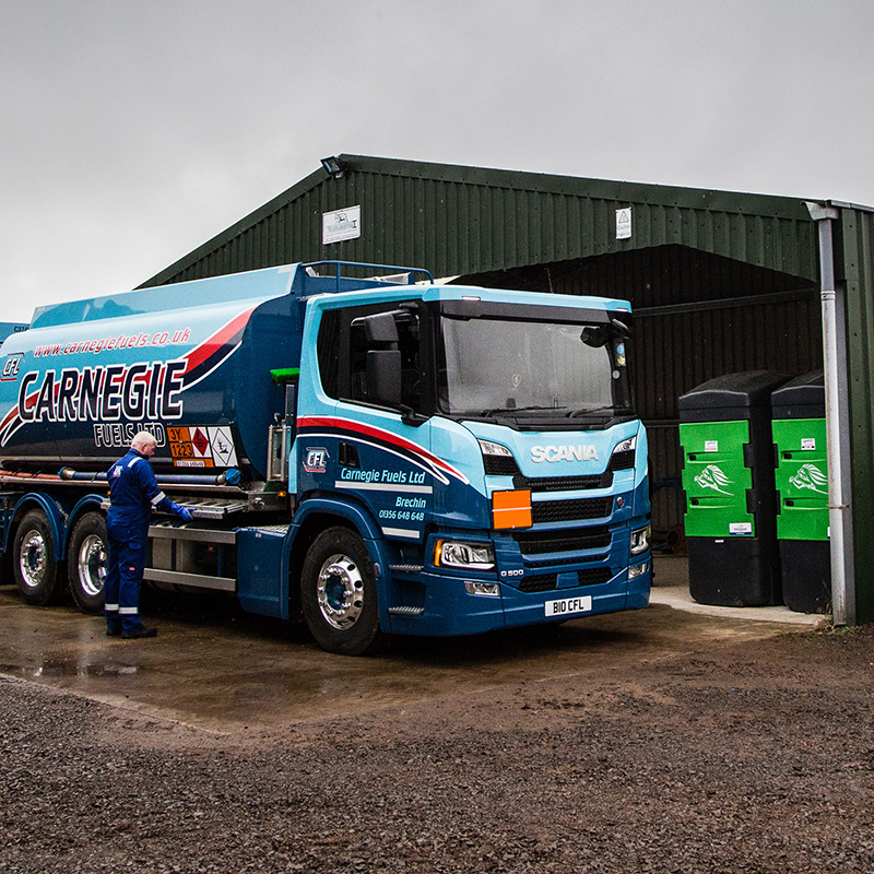 A Carnegie Fuels fuelling truck parked outside a an agricultural store with two oil tanks in it on a farm in Scotland