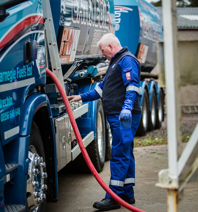 A Carnegie Fuels driver attending to the fuel hose that is connected to a fuelling tank.