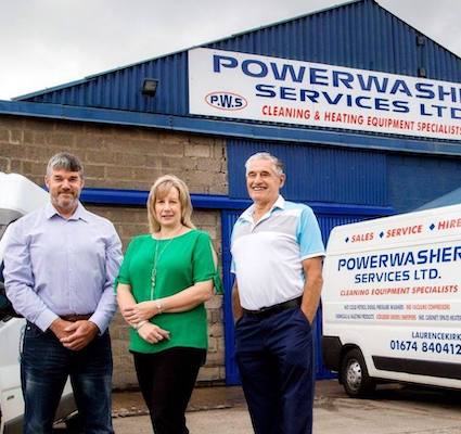 two men with a women standing between them in front of the PowerWasher Services building and van.