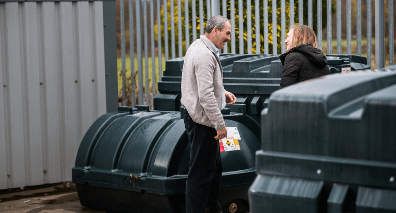 A man in a grey jacket being shown bunded oil tanks at the Carnegie Fuels