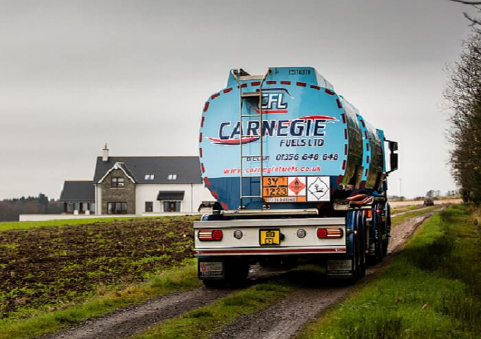 The back of a Carnegie Fuels fuelling truck driving along a farmland track to a house.